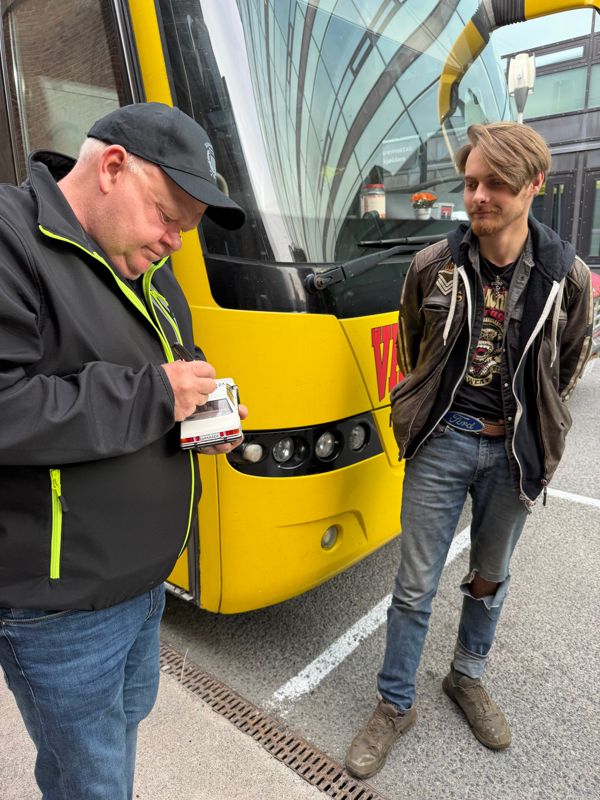 En Ford Granada-modellbil blir signert foran den gule bussen